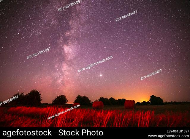 Agricultural Colorful Background Copy Space. Natural Real Night Sky Stars With Milky Way Over Field Meadow With Rolls Of Straw In Fields After Harvest