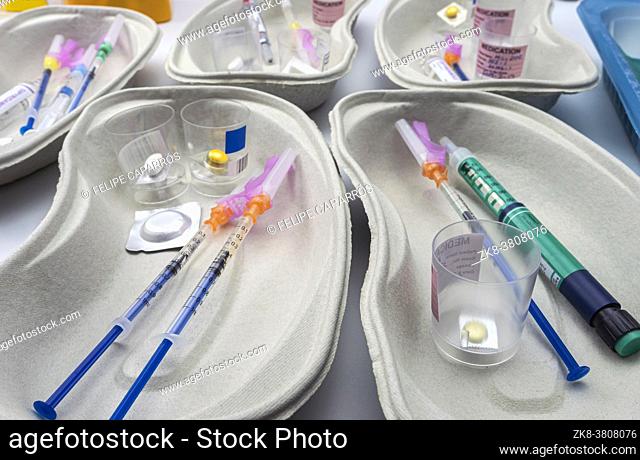Diverse medication in glasses monodose along with insulin injectors in hospital, conceptual image