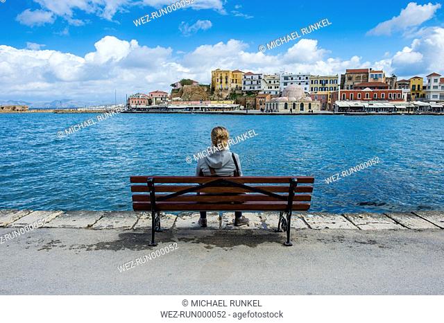 Greece, Crete, Chania, woman on bench at Venetian harbour