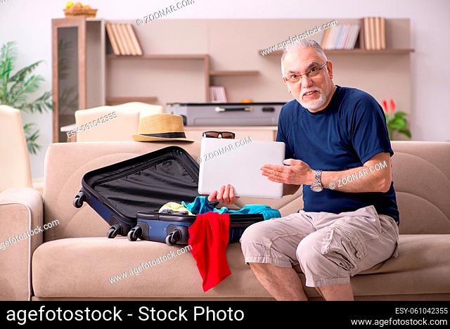 Old male tourist preparing for trip at home