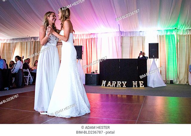 Caucasian brides dancing at wedding