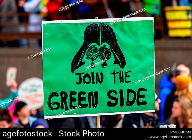 A close up view of a homemade sign during a street rally for the environment, depicting darth vader and saying join the green side