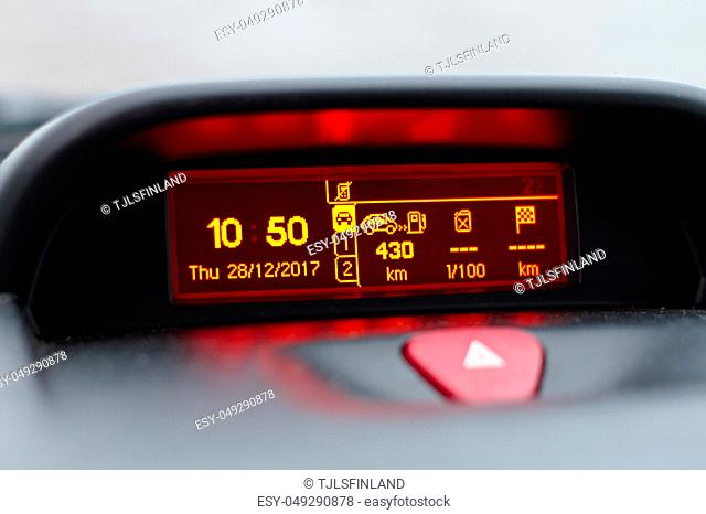On board computer showing date and time, fuel consumption info and trip length in kilometers. Also hazard warning lights button visible on foreground