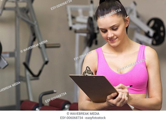 Female trainer writing on clipboard in gym
