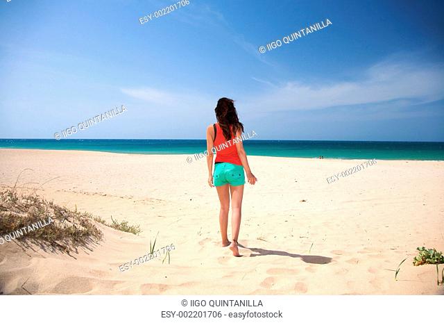 brown haired woman walking on the sand