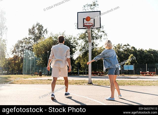 happy couple playing on basketball on playground