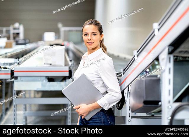 Confident young businesswoman with tablet PC at warehouse