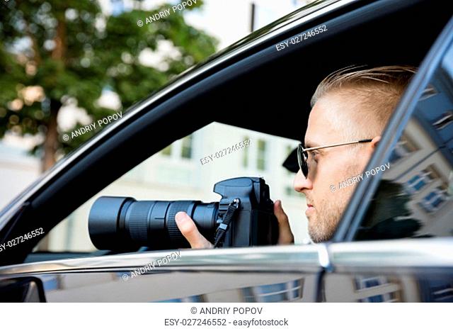 Man Doing Surveillance Sitting Inside Car Photographing With SLR Camera