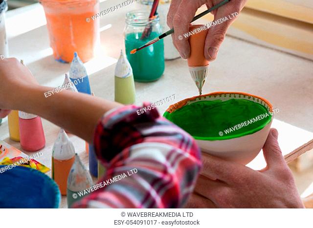 Male potter and girl painting bowl in pottery workshop