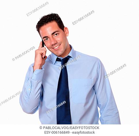 Portrait of an adult latin man on blue shirt and tie speaking using his cellphone while looking at you on isolated background