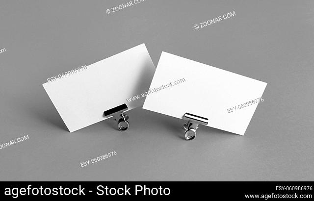 Two blank business cards and metal binder clips on gray background
