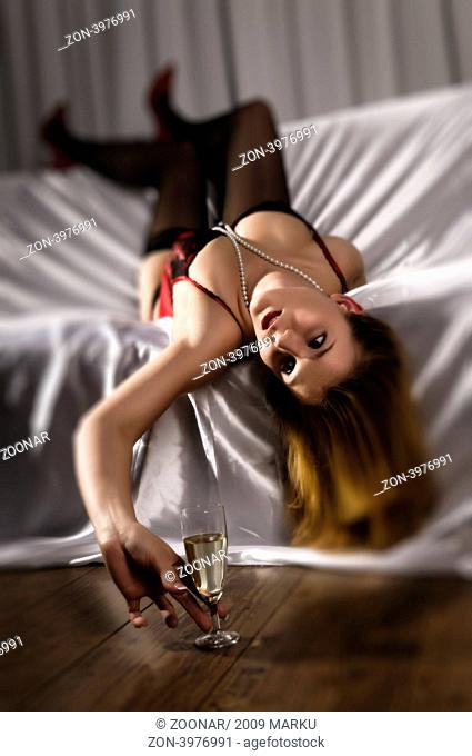 Attraktive junge Frau in roter Unterwäsche räkelt sich auf auf einem Sofa
