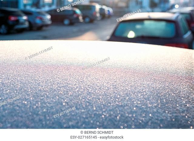 lights in the backlight of ice on a roof of a car in winter