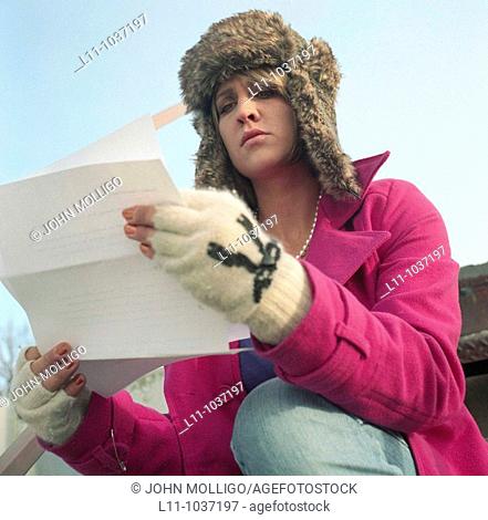 Woman in pink coat and ushanka, reading letter
