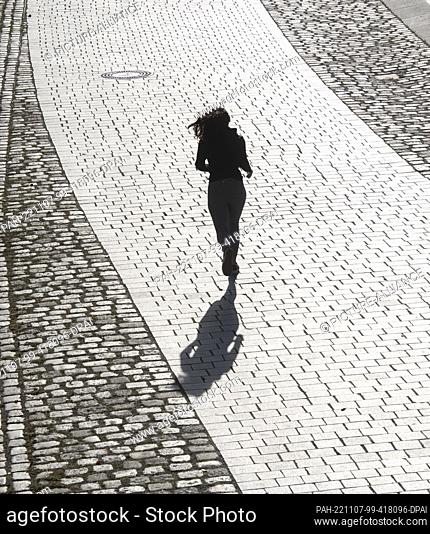 07 November 2022, Berlin: Only a silhouette of a jogger can be seen in the sunlight, walking in the government district. Photo: Paul Zinken/dpa
