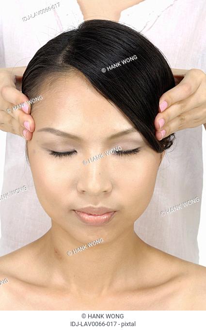 Young woman getting face massage from a massage therapist