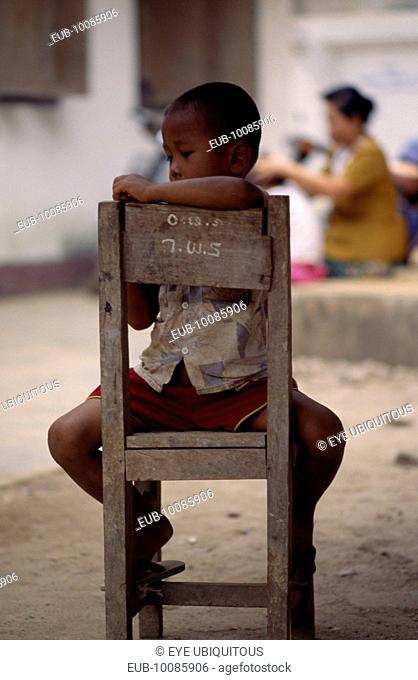 Karen refugee boy sitting on chair