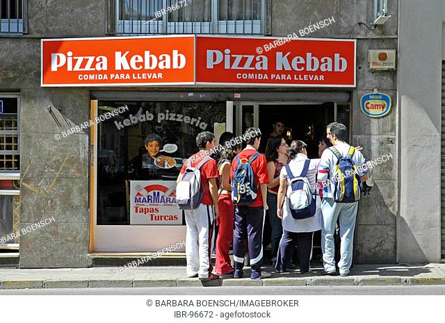 School children with rucksacks jostleling into the door of a pizza and kebab shope, Elx, Elche, Costa Blanca, Spain