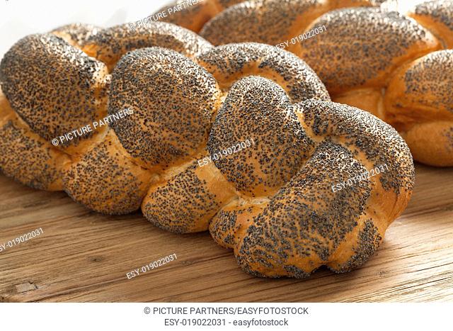 Two whole fresh Challah breads with poppy seeds