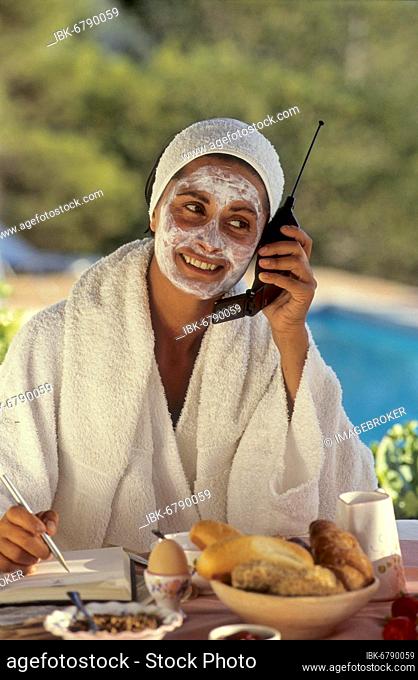 Cosmetics, woman with face mask on the phone, at breakfast