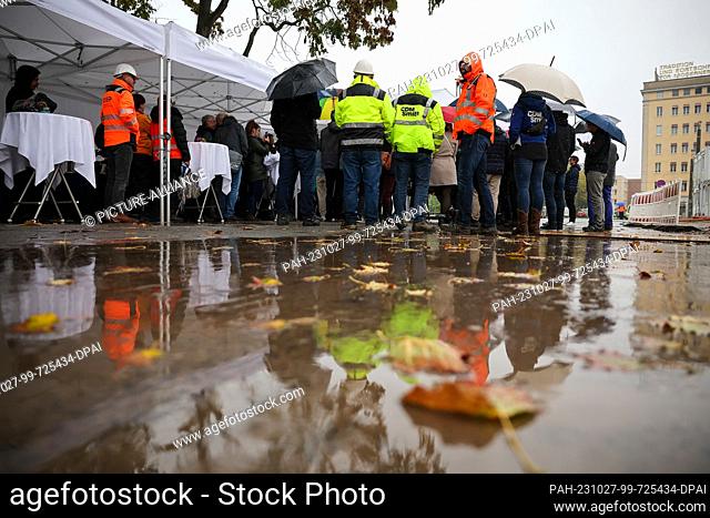 27 October 2023, Saxony, Leipzig: Guests and builders stand in the rain at the groundbreaking ceremony for the Leibniz Institute for Regional Geography (ifl)