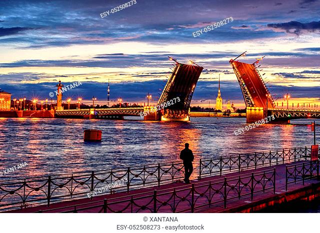 View through the opened drawbridge Palace Bridge and Neva river to Peter and Paul Fortress at white night time, St Petersburg, Russia