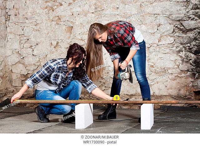Two long-haired young woman with an angle grinder