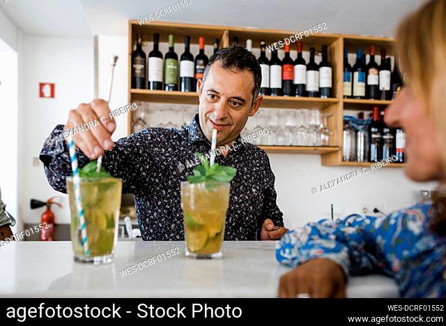 Bartender preparing cocktail at bar counter in restaurant