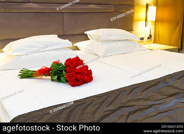 Bouquet of red roses on the bed in a hotel room. Romantic meeting of guests at the hotel honeymoon. romantic getaway for your beloved