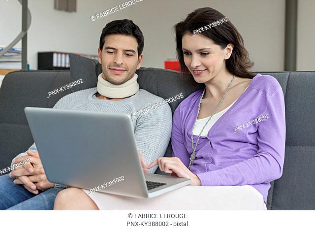 Woman using a laptop with her husband beside her