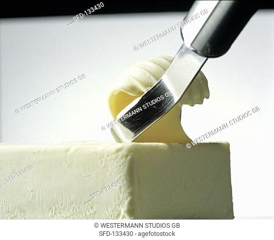 Utensil Slicing a Butter Curl From a Stick of Butter