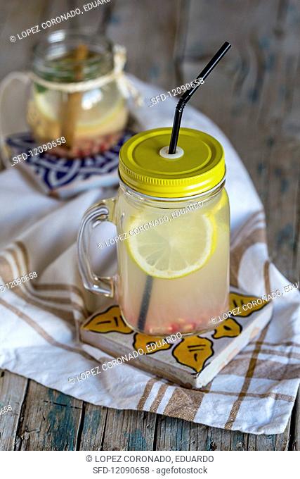 Lemonade with fresh lemon, mint, cinnamon and quince on a wooden surface