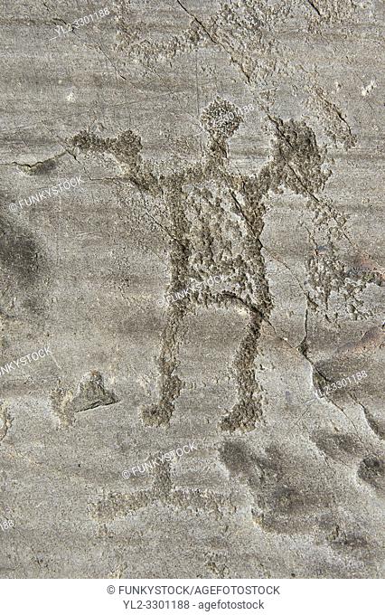 Petroglyph, rock carving, of a warrior holding swords and shields. Carved by the ancient Camuni people in the iron age between 1000-1600 BC