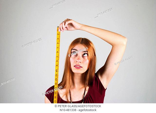 Young woman, with long red hair, using a tape measure
