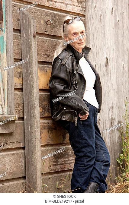 Older Caucasian woman leaning on wooden wall