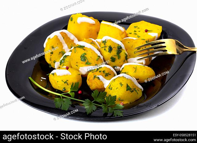 Baked potatoes sprinkled with herbs on a black plate
