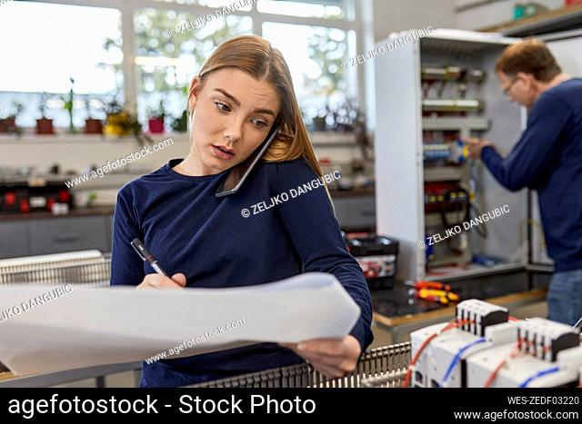 Young woman on the phone in electrical workshop