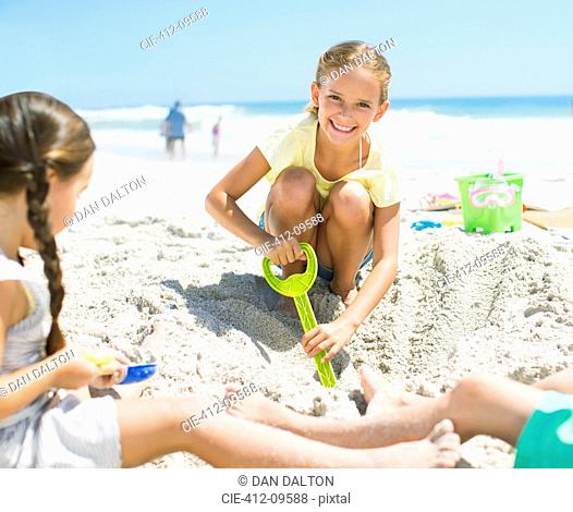 Girls digging in sand on beach