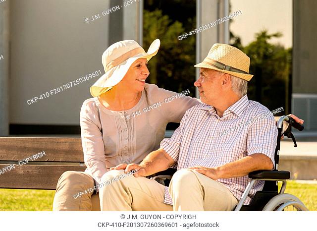 Senior disabled man and wife talking outdoors in park