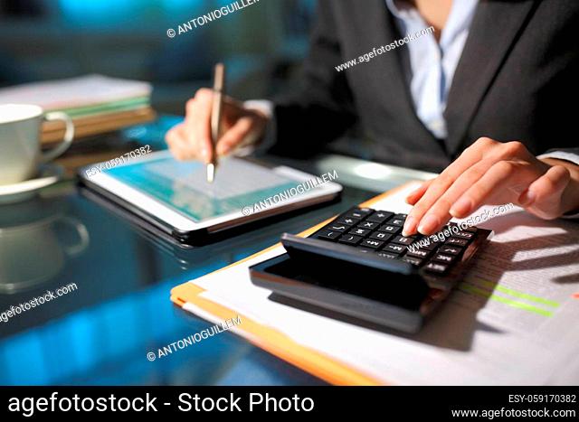 Close up of a businesswoman hands using tablet and calculator in the night at homeoffice
