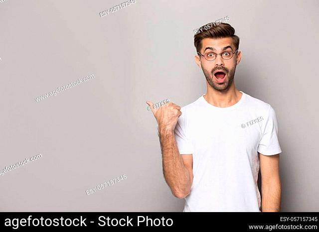 Amazed funny guy wearing white t-shirt glasses point finger aside at copy space advertise better offer huge discount opportunity