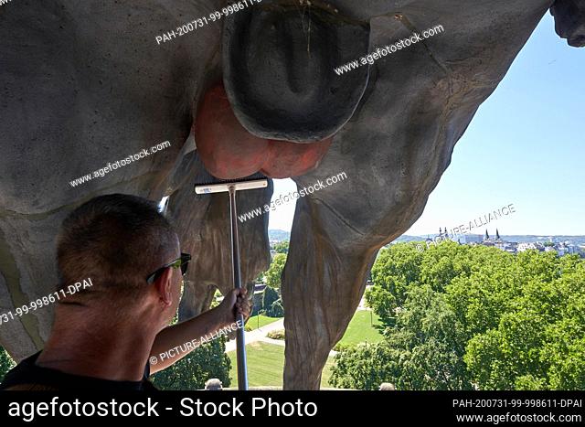 31 July 2020, Rhineland-Palatinate, Koblenz: Cleaning staff remove red paint that sprayers have sprayed on the horse's privates at the equestrian statue of...