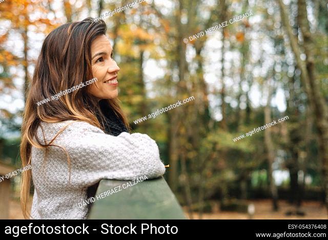 Attractive woman, relaxed in a park In autumn surrounded by colorful leaves looking to the trees pensively