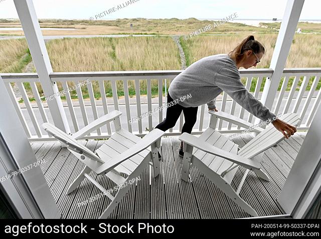 12 May 2020, Schleswig-Holstein, St.Peter-Ording: Kati Simon, hotel employee at the Beach Motel, arranges the chairs on the balcony of a hotel room