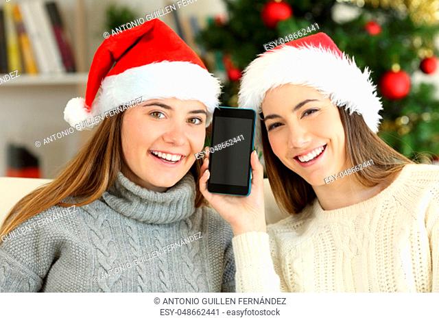 Happy girls showing a blank phone screen on christmas