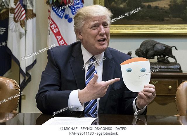 US President Donald J. Trump holds up a note and drawing depicting him that was created by the child of Greg Knox of Ohio