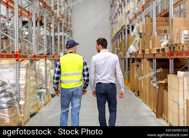 worker and businessman walking along warehouse