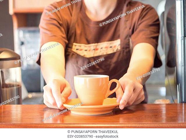 Barista offering orange cup of coffee