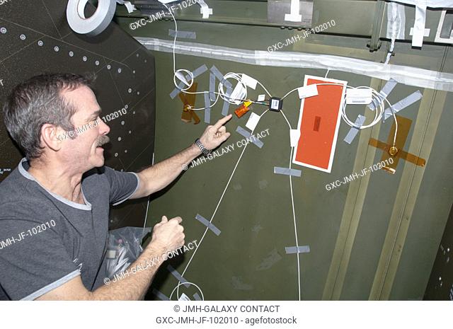 Canadian Space Agency astronaut Chris Hadfield, Expedition 34 flight engineer, installs Ultra-Sonic Background Noise Tests (UBNT) sensors behind a rack in the...