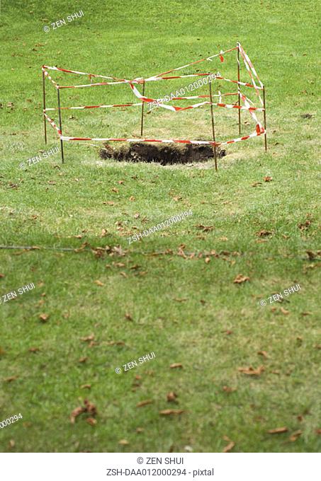 Hole in grass, roped off with barrier